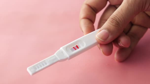 Mano sosteniendo kit de prueba de embarazo en rosa — Vídeos de Stock