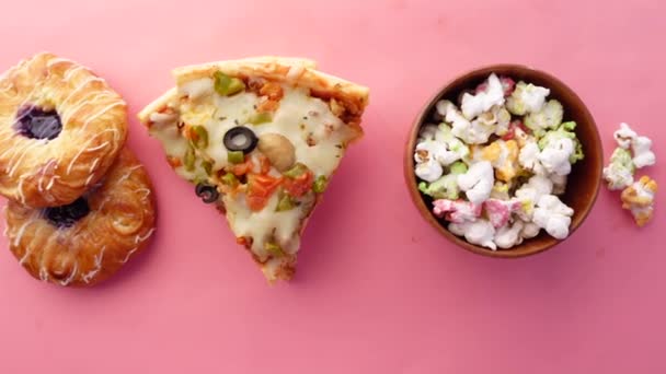 盘子里的奶酪比萨饼，粉红色的甜甜圈和爆米花 — 图库视频影像