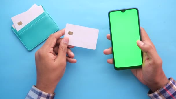 Mann hält Kreditkarte in der Hand und kauft mit Smartphone online ein — Stockvideo