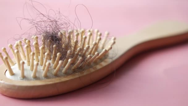 Un cepillo con el pelo perdido sobre fondo rosa — Vídeos de Stock