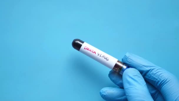 Primer plano del tubo de análisis de sangre del virus delta corona de mano sobre fondo azul — Vídeos de Stock