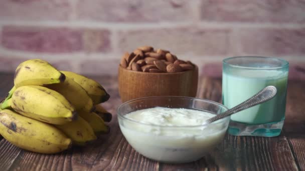 Yogurt fresco in una ciotola, banana, mandorla e latte in tavola — Video Stock