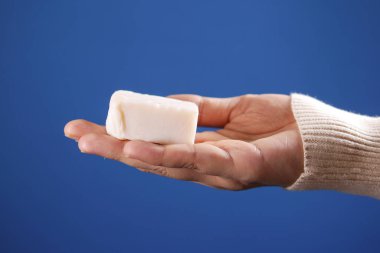 Kadınlar el yapımı sabunu mavi arka planda tutarlar. 