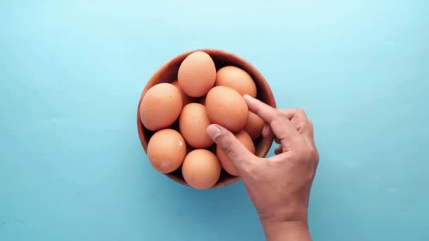 Рука вибирати яйця з пластикового футляру на столі — стокове відео