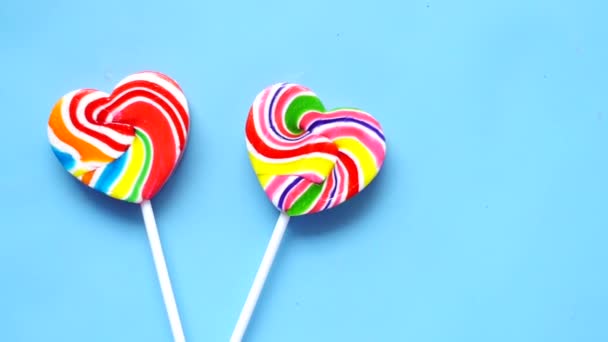 Arco iris corazón forma caramelo sobre fondo azul — Vídeos de Stock