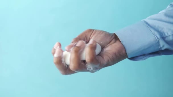 年轻人用肥皂在蓝色背景下洗手 — 图库视频影像