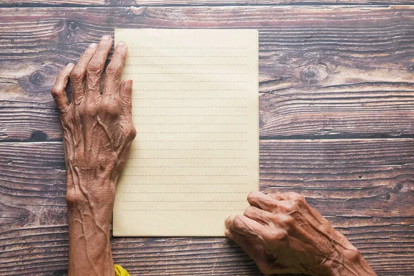 Top view of senior woman hand on blank paper on table — Stock Photo, Image