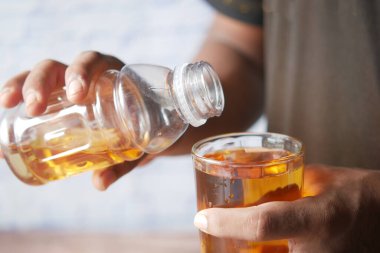 Genç adam elma suyunu bardakta somurtuyor. 