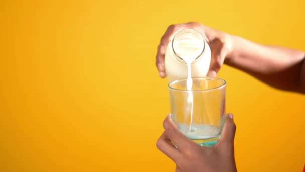 Versando il latte nel bicchiere sullo sfondo giallo — Video Stock