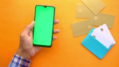 Adamın biri kredi kartını tutuyor ve online akıllı telefon alışverişi yapıyor. 