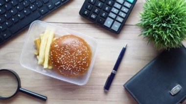 Ofis masasındaki yemek kutusunda sığır burger ve Fransız arkadaş.