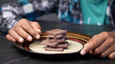 Çocuk tabakta siyah çikolata topluyor. 