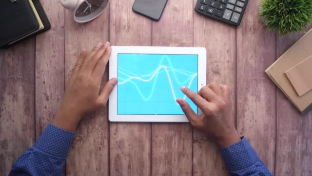 Рука чоловіка, що працює на цифровому планшеті на офісному столі, використовуючи самостійно створену діаграму — стокове відео