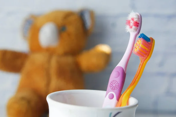 Colorful child toothbrushes in white mug against a wall — Stock Photo, Image