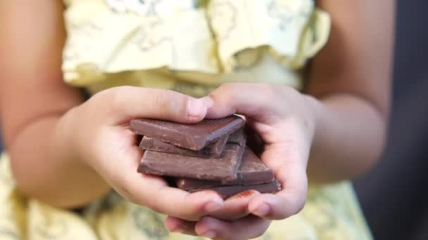 Девочка держит темный шоколад — стоковое видео