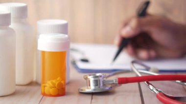 Doktor el yazısı reçetesi masada, masada ilaç kutusu var. 