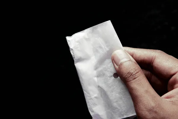 Drugsverslaving concept met hand holding heroïne pakket op zwarte backgrund — Stockfoto