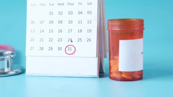 Stetoskop, medicinska piller behållare och kalender på färg bakgrund — Stockvideo