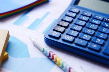 Masadaki mavi hesap makinesini ve finansal grafiği kapat.