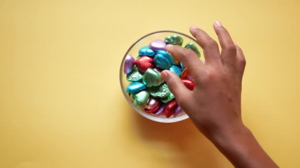 Kind Junge Hand wählen dunkle Schokolade auf gelbem Hintergrund — Stockvideo