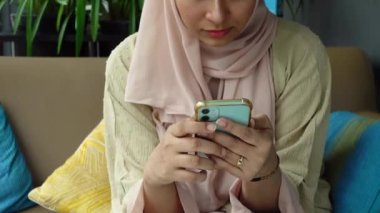 Genç kadınlar otururken ellerinde akıllı telefonlar tutuyorlar. 