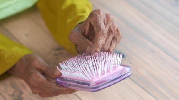 Senior women hand hold a brush with lost hair on white background — Stock Video
