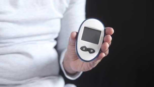 Mans hand houden glucosemeter geïsoleerd op zwart — Stockvideo