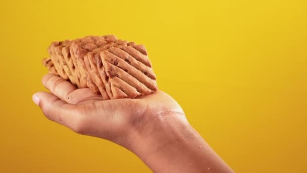 Kies koekje met de hand tegen gele achtergrond — Stockvideo