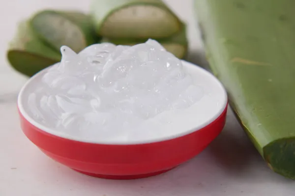 Gel fresco di aloe vera affettato e liquido in contenitore di plastica su fondo bianco — Foto Stock