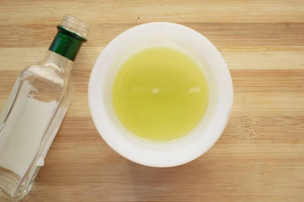 Olivový olej v misce a prázdná láhev na stole — Stock fotografie