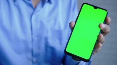 Yeşil ekranlı akıllı telefon kullanarak genç adamın elini kapat. 