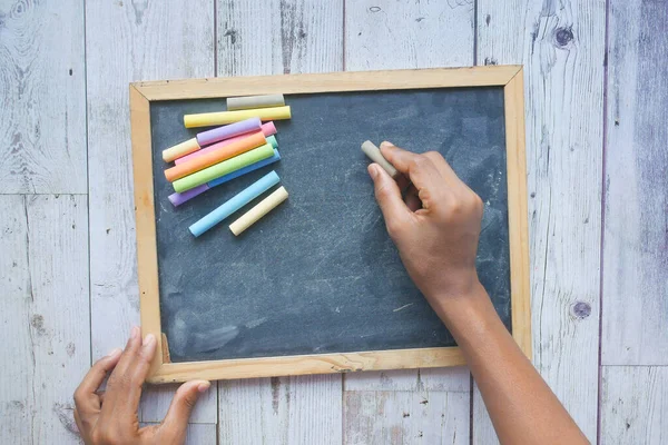 Дитячий малюнок рукою з барвистим крейдою на крейдяній дошці на чорному фоні — стокове фото