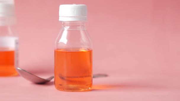 Butelka z lekiem w płynie na różowym tle — Wideo stockowe