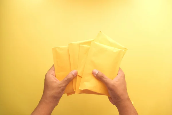 El ele tutuşan sarı kağıt baloncuk zarf üst görünüm — Stok fotoğraf