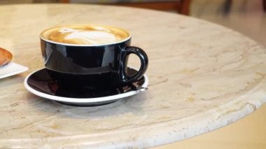 Kafenin tepesinde çiçek desenli geç kalmış bir fincan kahve. 