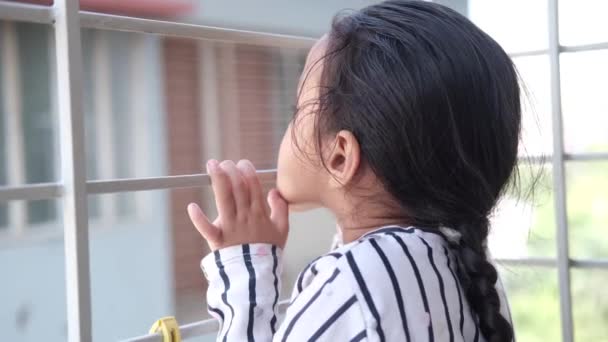 Niño triste niña mirando a través de la ventana — Vídeos de Stock