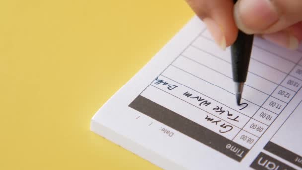 Schrijven op een dagelijkse planner op tafel. — Stockvideo
