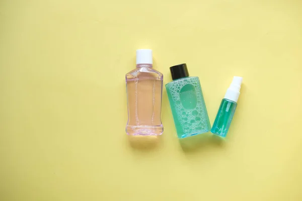 Mundspülmittel in einem Behälter auf gelbem Hintergrund — Stockfoto