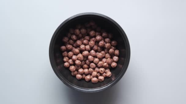 Flocons de maïs au chocolat versant dans un bol sur rose — Video