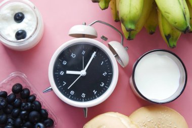 Pembe arka planda sağlıklı meyve ve eski çalar saat 