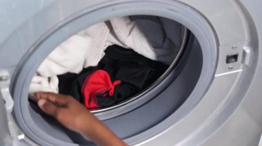 bir çamaşır makinesine havlu ve bez koymak.