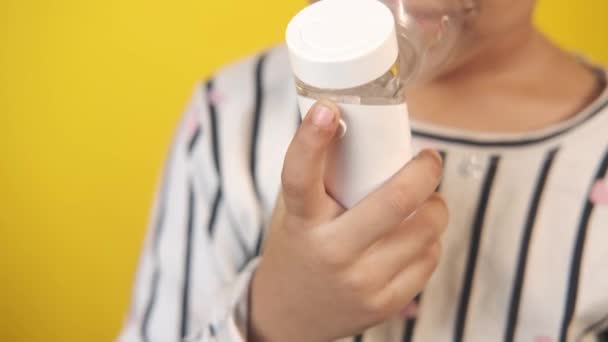 Enfant fille main tenir un nébuliseur sur fond jaune — Video