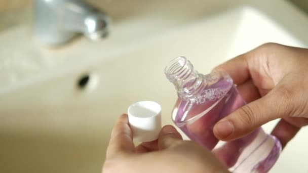 Mulheres mão segurar um recipiente líquido de enxaguamento bucal — Vídeo de Stock