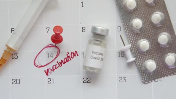 Концепт дня вакцины стеклянная ампула с вакциной и шприц на календаре — стоковое видео