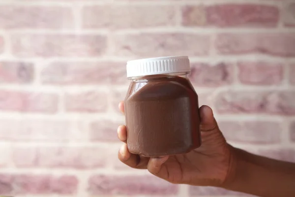 Рука держит шоколадный крем из ореха в контейнере — стоковое фото