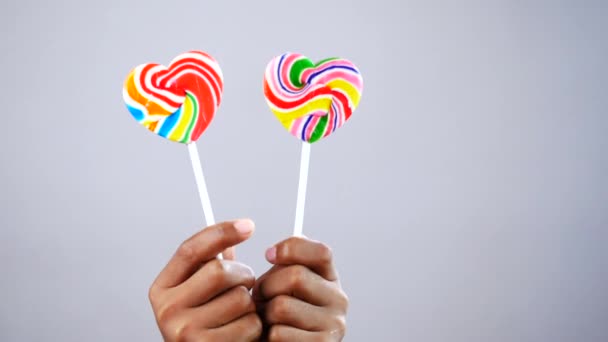 Hand hält Lutscher in Regenbogenform — Stockvideo