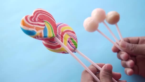 Mano tenere caramelle a forma di cuore arcobaleno su rosa — Video Stock