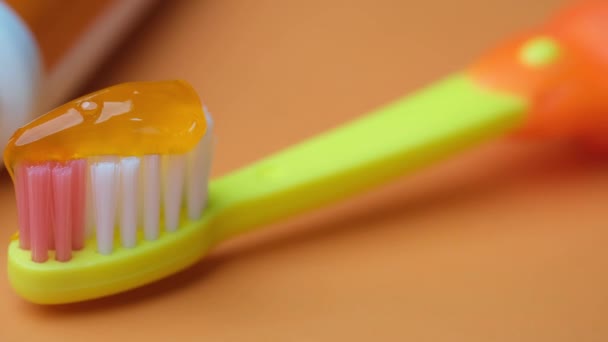 Cepillo de dientes para niños y pasta sobre fondo naranja — Vídeo de stock