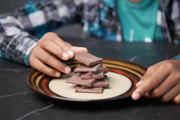 Child boy hand pick dark chocolate on a plate — Stock Photo, Image