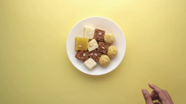 Vista superior da mão escolher indiana doce em uma tigela na mesa. — Vídeo de Stock